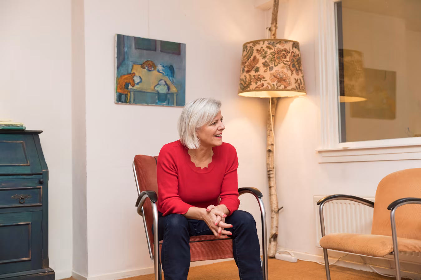 Binnenruimte met zithoek en glimlachende persoon, sfeerimpressie passend bij begeleiding en positieve psychologie